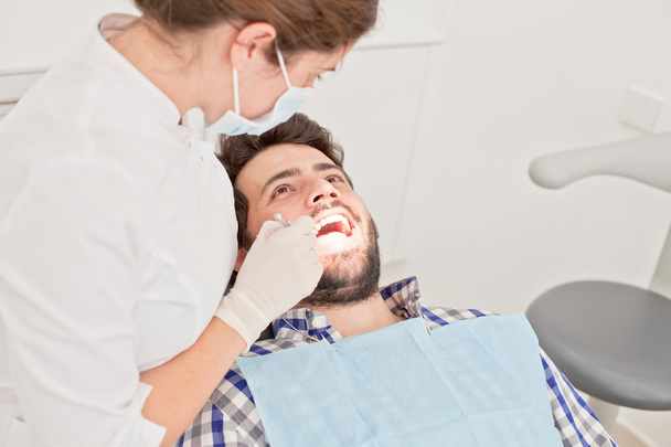 молодой счастливый мужчина и женщина на стоматологическом осмотре у стоматолога
 - Фото, изображение