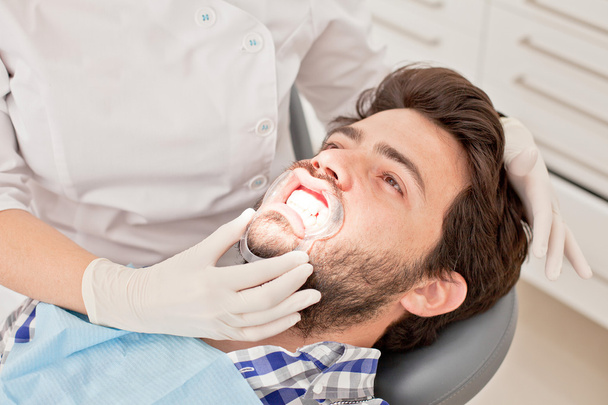 молодой счастливый мужчина и женщина на стоматологическом осмотре у стоматолога
 - Фото, изображение