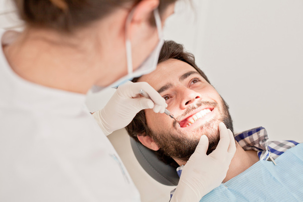 młody człowiek szczęśliwy i kobieta w badanie stomatologiczne u dentysty - Zdjęcie, obraz