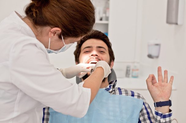 χαρούμενος νεαρός και μιας γυναίκας σε μια οδοντική εξέταση σε οδοντίατρο - Φωτογραφία, εικόνα