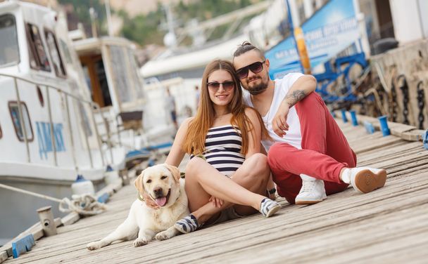 Young couple on a walk in the Harbor with a white Labrador - 写真・画像