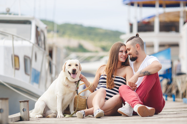 Young couple on a walk in the Harbor with a white Labrador - Фото, зображення
