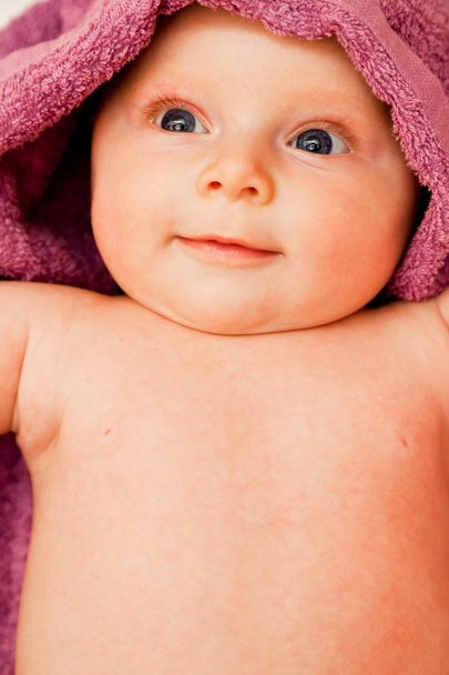 Infant baby girl smiling laying in violet towel - Fotografie, Obrázek