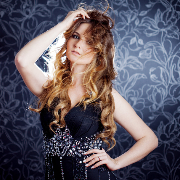 beautiful girl  with long brown curled hair, dark background - Foto, Imagen
