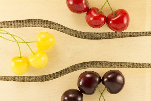 Colorful cherries in a wooden spatula on a natural fabric - Fotoğraf, Görsel