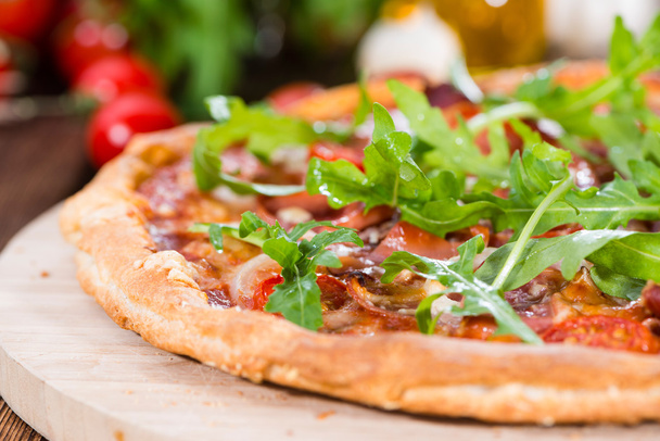 Schinken-Pizza mit Rucola und frischen Tomaten - Foto, Bild