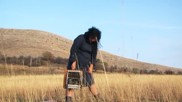 Grappige vrouw in zwarte kruipende met typemachine in de natuur - Video