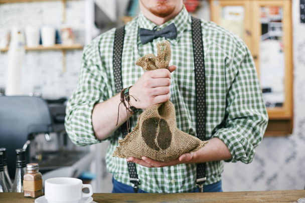 Бариста держит мешок с зерном кофе
 - Фото, изображение