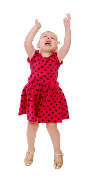 Loira menina em um vestido de bolinhas vermelhas salta seus braços levantar
 - Foto, Imagem