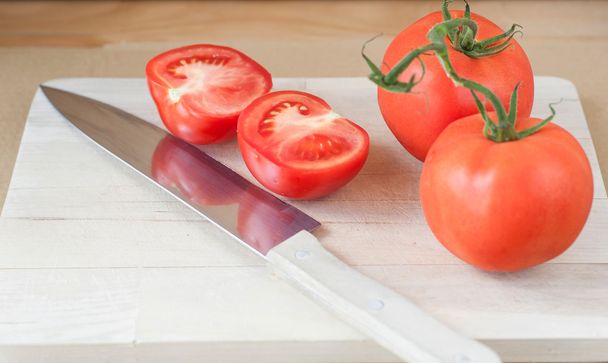 Freshly sliced tomato with knife - Foto, afbeelding