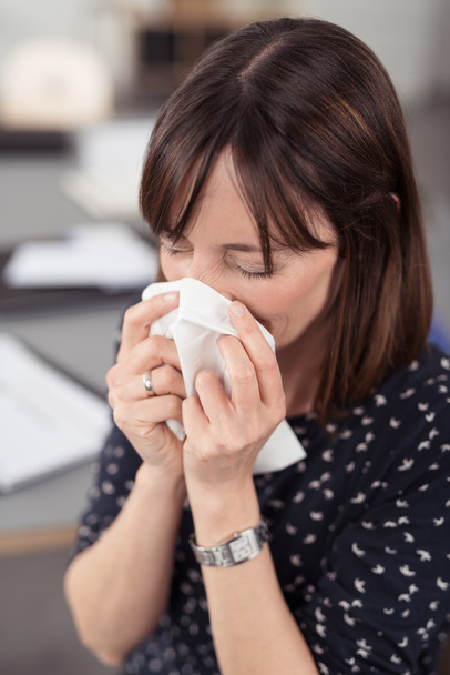 Sick Businesswoman Sneezing Into a Tissue - Фото, зображення
