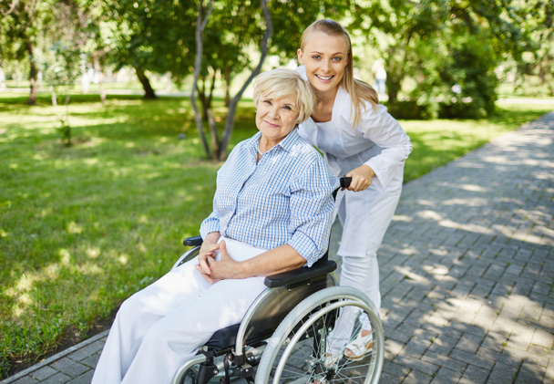 Gezondheidszorg assistent en leeftijd vrouw in een rolstoel - Foto, afbeelding