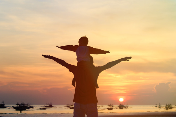 vader en zoon plezier op sunset beach - Foto, afbeelding