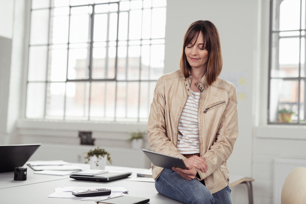 Businesswoman sitting on her desk using a tablet - Foto, Imagen