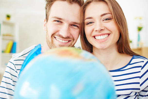 Couple with toothy smiles  and globe - Photo, Image