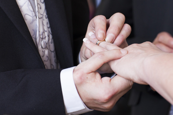 Groom placing ring on bride's finger - Fotó, kép