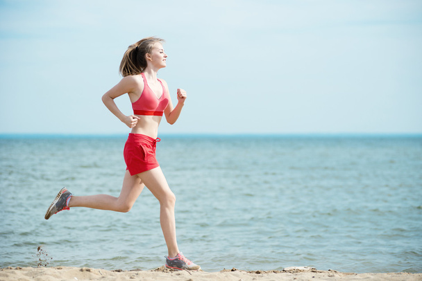 Юная леди бежит на солнечном летнем песчаном пляже. Тренировка. Бег
 - Фото, изображение
