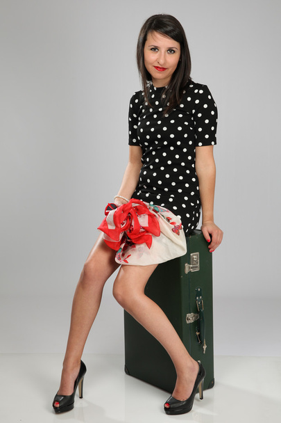 Dame im Vintage-Outfit sitzt auf einem Koffer - Foto, Bild