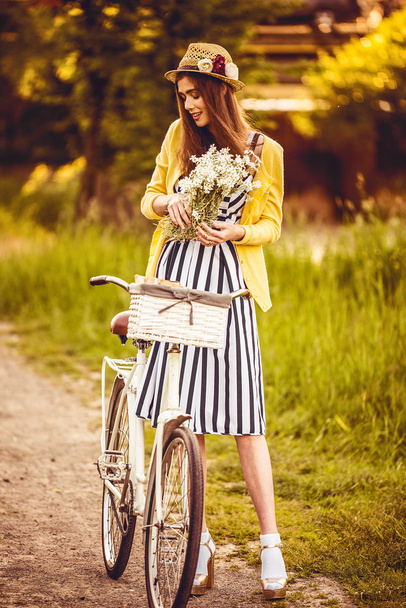 Hipster fashion girl in straw hat keep beauty flowers  - 写真・画像
