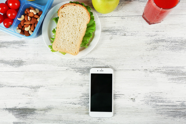 Food and mobile phone on wooden background - Foto, afbeelding