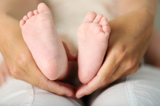 Adult hands holding baby feet, closeup - Foto, imagen