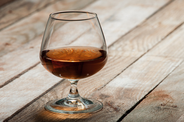 Cognac glass on a wooden table - Фото, изображение