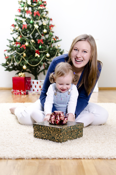 kleines Mädchen und ihre Mutter packen das Weihnachtsgeschenk aus - Foto, Bild