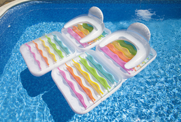 Colorful floating air mattresses in swimming pool at summertime  - Photo, Image
