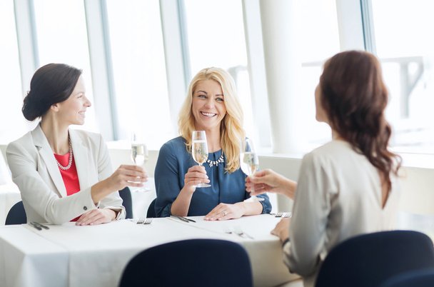 happy women drinking champagne at restaurant - Foto, Imagen