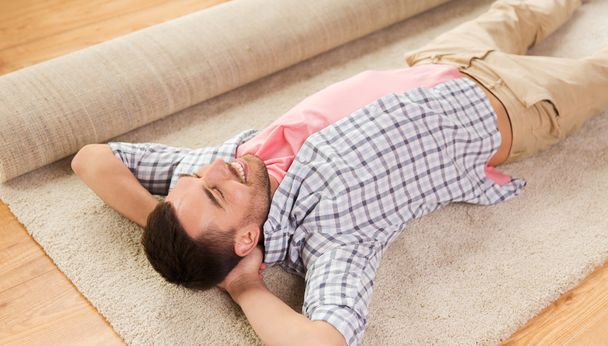 happy man lying carpet or rug at home - Zdjęcie, obraz