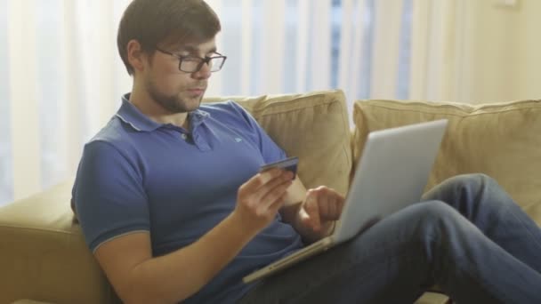 Man Laying on Couch and Using Laptop for Online Shopping at Home - Materiał filmowy, wideo