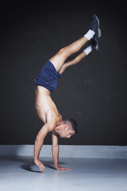Muscular athlete doing a one arm handstand - Photo, Image