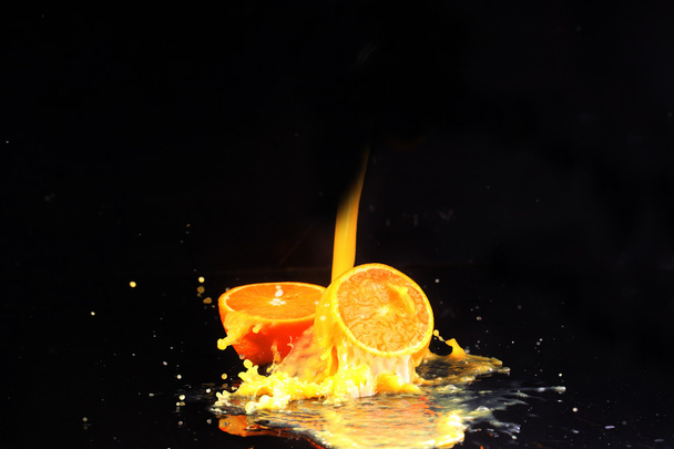 Turuncu Siyah bir arka plan üzerinde portakal portakal suyu akar - Fotoğraf, Görsel