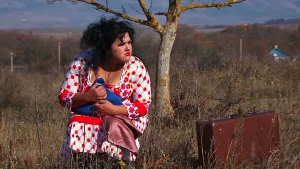 Femme étrange en robe à pois blanc assis près de la valise à la nature
 - Séquence, vidéo
