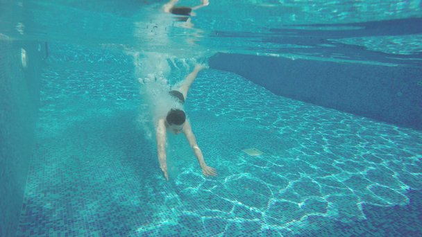 Молодий чоловік занурюється в басейн, насолоджуючись перебуванням на курорті
 - Кадри, відео