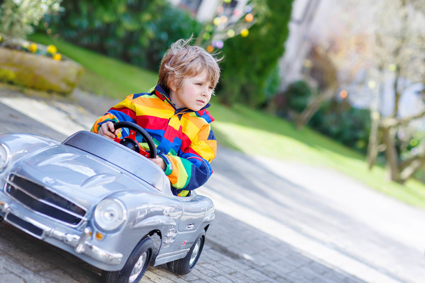 Pequeno menino pré-escolar dirigindo grande brinquedo velho carro vintage, ao ar livre
 - Foto, Imagem