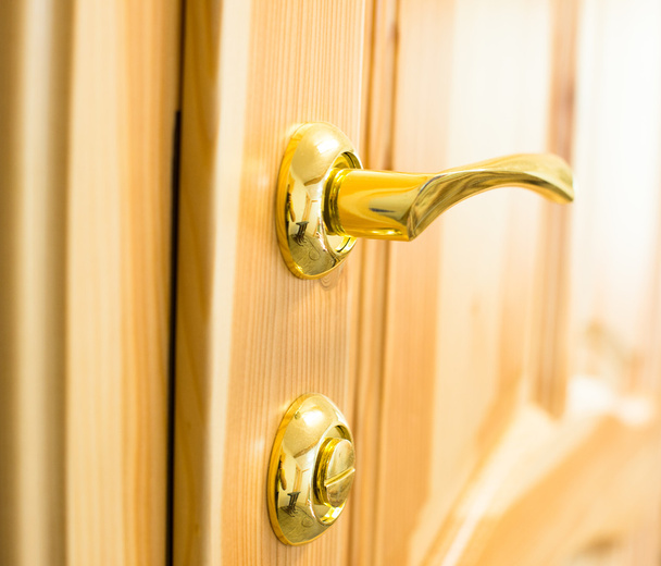 Poignée de porte dorée et serrure sur la porte en bois
 - Photo, image