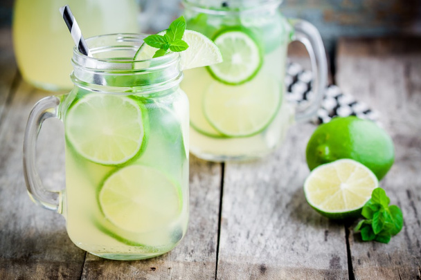 homemade lemonade with lime, mint in a mason jar on a wooden table - Photo, Image