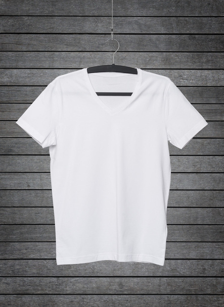 Close up of a V shape white t-shirt on cloth hanger. Dark concrete background. - Foto, afbeelding