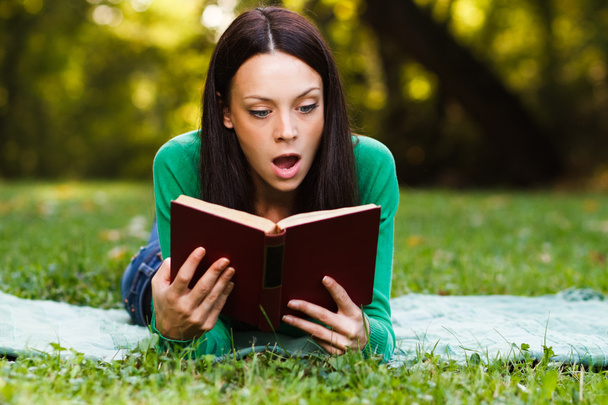 woman is surprised about something she had read in a book - Foto, afbeelding