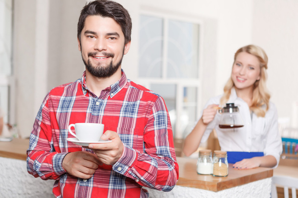 Smiling man with coffee on background of waitress - Φωτογραφία, εικόνα