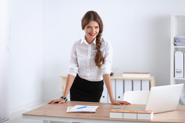 Attractive businesswoman standing in office - Foto, afbeelding