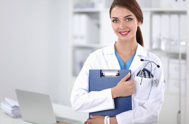 Smiling female doctor with a folder in uniform standing at hospital - Photo, Image