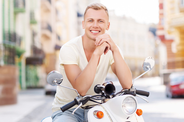 Blond-haired man leaning on scooter  - Foto, Imagen