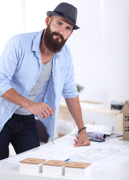 Portrait of male designer in hat with blueprints at desk  - Foto, immagini
