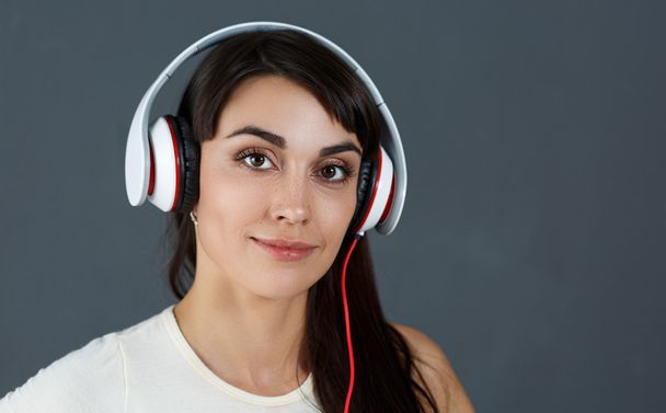 Beautiful dark haired smiling woman wearing headphones - Fotoğraf, Görsel