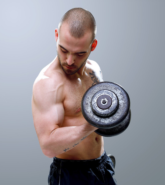 Young, masculine and fit man lifting dumbells - Foto, afbeelding