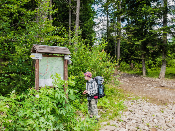 Молодий турист поблизу схеми гірських маршрутів
 - Фото, зображення