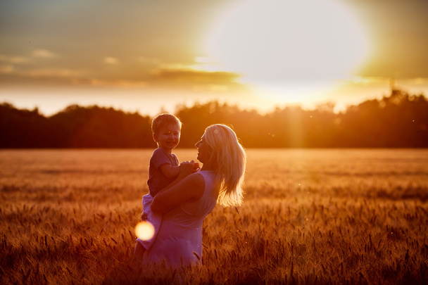 Mutter und Sohn amüsieren sich am See, das Feld im Freien genießt die Natur. Silhouetten am sonnigen Himmel. warmer Filter und Filmeffekt - Foto, Bild