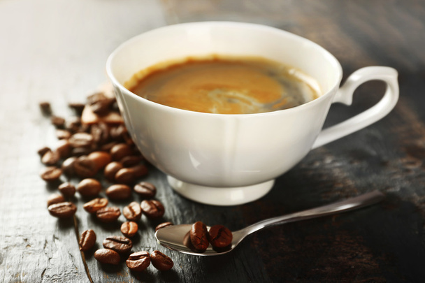 Cup of coffee with beans on table, closeup - Photo, image